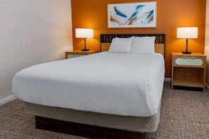 Una cama bien hecha con sábanas blancas, dos mesitas de noche con lámparas y un cuadro en la pared.