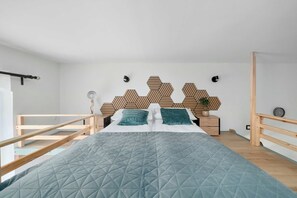 Ein modernes Schlafzimmer mit einem Bett, einem Holzkopfteil, Nachttischen und Blick ins Freie.