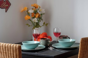 Ein Tisch mit türkisfarbenen Schalen, einem Glas Rotwein, einem Glas Roséwein, einer Keramiktasse und einer Vase mit Blumen.