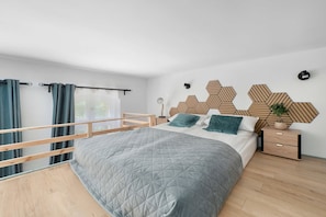 Un dormitorio moderno con cama, mesita de noche, lámpara de pared y decoración geométrica en la pared.