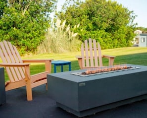 Un espace extérieur aménagé avec des chaises Adirondack et un foyer rectangulaire.