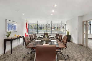 A conference room with a large table, chairs, a flag, and a window view. - Vancouver | Urban Group Retreat | Walkable + Sauna | 2BR (Vancouver)