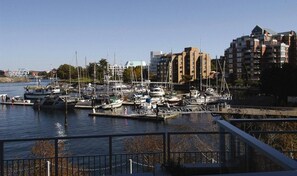 Un port esportiu amb vaixells amarrats, un pont al fons i edificis amb balcons.