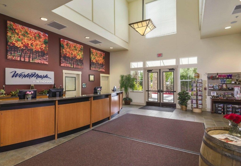 A reception area with a wooden counter, framed artwork, a sign reading 'Worldmark at Wyndham,' and a glass door entrance.
