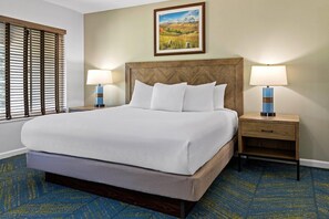 A hotel room with a large bed, two bedside tables with lamps, a painting on the wall, and a window with blinds. - Wolf Creek | Family Ski Retreat | Pool + Ski | 2BR (Eden)
