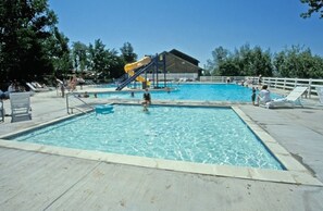 A swimming pool with a slide, lounge chairs, and a covered area. - Wolf Creek | Cozy Ski Retreat | Pool + Ski | 2BR (Eden)