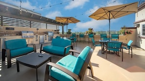 Una terrazza esterna con posti a sedere, un barbecue e ombrelloni.