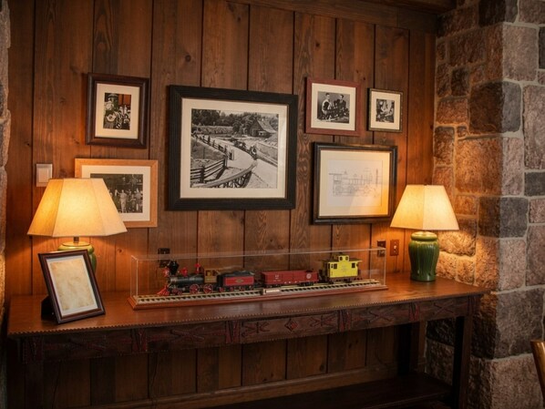Pared de madera con fotografías enmarcadas y un modelo de tren.