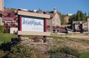 Schild für Wyndham by Wyndham in einer begrünten Anlage mit Häusern im Hintergrund.