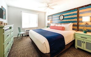 A hotel room with a bed, a desk, a chair, a window, and a wall with a striped pattern. - San Diego | Friends Beach & City Trip | Pool + Hot Tub | 2BR (San Diego)