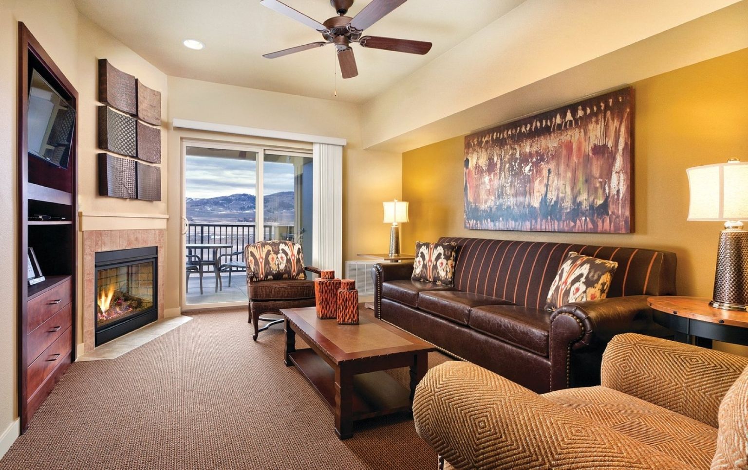 A living room with a fireplace, a sofa, a coffee table, and a view of the outdoors.