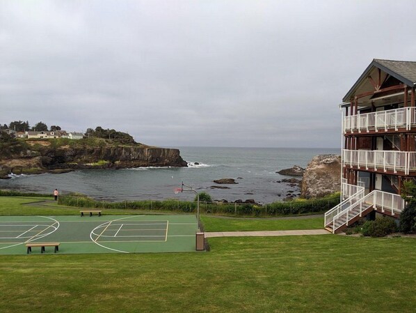Vistes costaneres amb una pista de tennis, un edifici amb balcó i penya-segats rocosos.