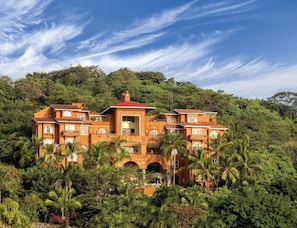Un edificio grande de varios pisos con un patio central, rodeado de exuberante vegetación tropical.