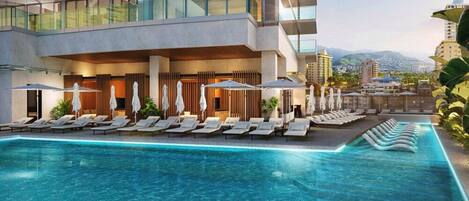 A modern hotel with a pool, sun loungers, and umbrellas.