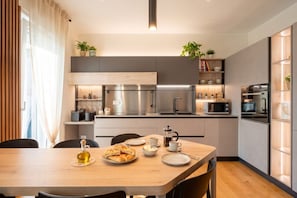 Eine moderne Küche mit Edelstahlgeräten, einem Holztisch und Blick auf die Stadt.