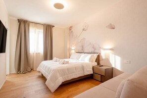 Ein Schlafzimmer mit einem Bett, Nachttischen, einer Wandlampe und einem Fenster mit Vorhängen.