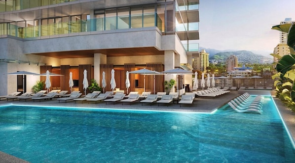 Un hotel moderno con piscina, tumbonas y sombrillas.