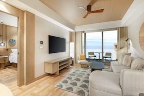 Un salon moderne doté d’un téléviseur à écran plat, de meubles en bois, d’un ventilateur de plafond et offrant une vue sur la mer.