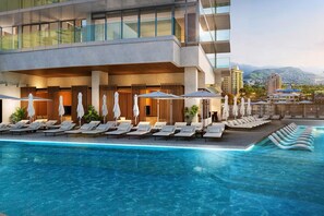 Un hotel moderno con piscina infinita en la azotea, sillones de descanso y vistas a la ciudad.