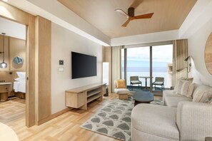 Un salon moderne doté d’un téléviseur à écran plat, de meubles en bois, d’un ventilateur de plafond et offrant une vue sur la mer.