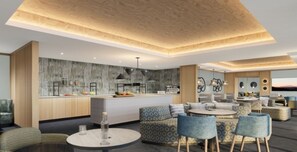 Una cocina moderna con una isla central, un área de comedor con mesas redondas y una sala de estar con sofás y televisor.