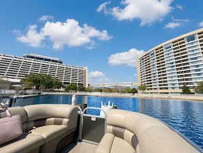 Un bateau équipé de sièges, offrant une vue sur la piscine d’un hôtel à plusieurs étages, avec un pont en arrière-plan.
