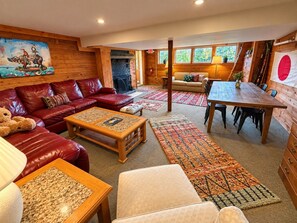Una sala de estar acogedora con un sofá de cuero rojo, una mesa de centro de madera y un comedor con una mesa y sillas de madera.