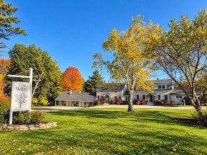 A two-story house with a well-maintained lawn and a sign indicating the property name. - Wiley Inn | Rustic Retreat with Jetted Tub and Corner Shower (Peru)
