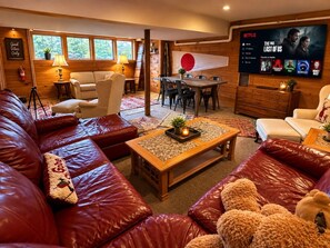 A cozy living room with leather sofas, a coffee table, and a TV displaying a Netflix interface. - The Wiley | Stylish Queen Room Near Ski Bar (Peru)