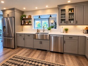 A modern kitchen with stainless steel appliances, grey cabinetry, and a large window providing natural light. - The Wiley | Stylish Queen Room Near Ski Bar (Peru)