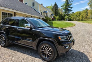 A black SUV parked on a gravel driveway in front of a residential home. - The Wiley | Stylish Queen Room Near Ski Bar (Peru)