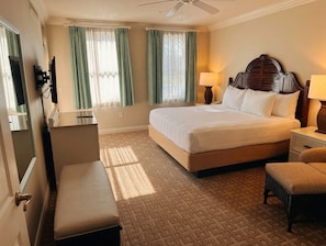 A hotel room with a large bed, a desk, a chair, a television, and a ceiling fan. - Orlando | Laid-Back Island Escape | Pool + Golf (Lake Buena Vista)