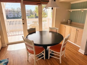 A dining area with a round table and four chairs, a ceiling lamp, and a view of a deck and houses through glass doors. - Orlando | Laid-Back Island Escape | Pool + Golf (Lake Buena Vista)