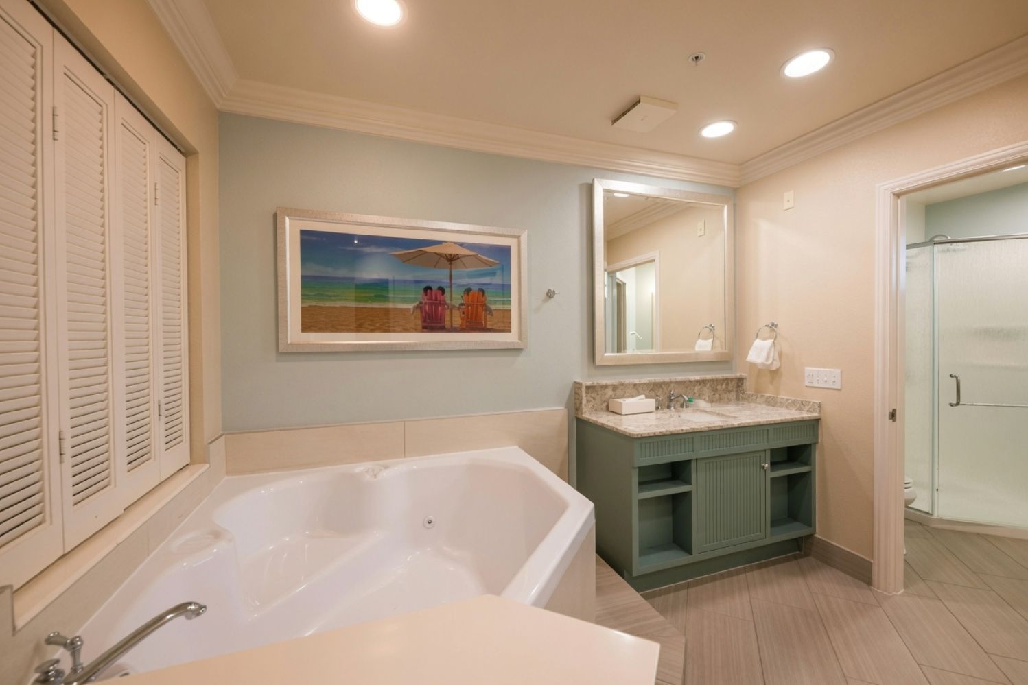 A bathroom with a bathtub, a vanity with a mirror, and a painting on the wall.