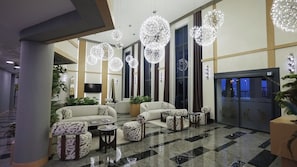 A hotel lobby with a checkered floor, seating area with patterned sofas, and decorative spherical light fixtures. - Lorent Hotel İncek (Ankara)