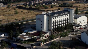 Un gran edificio de hotel con un cartel llamativo, varios pisos y un área de estacionamiento.