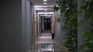 A hotel hallway with a clear path to the exit, a fire extinguisher, and a plant on the right. - Lorent Hotel İncek (Golbasi)
