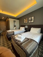 Una habitación de hotel con dos camas, un escritorio, una silla y obras de arte en la pared.