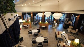 A spacious indoor area with multiple seating arrangements, including round tables and chairs, and a variety of plants and decorative elements. - Lorent Hotel İncek (Golbasi)
