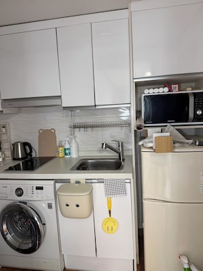 A kitchen with white cabinets, a stainless steel sink, a microwave, a washing machine, and a refrigerator. -  10 Min to Hongik Univ. Station 6min to Bus Stop (Seoul)