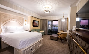 A hotel room with a large bed, a desk, a chair, a television, and a balcony with a view. - Orlando | Cozy Riviera Retreat | Pool + Resort (Lake Buena Vista)