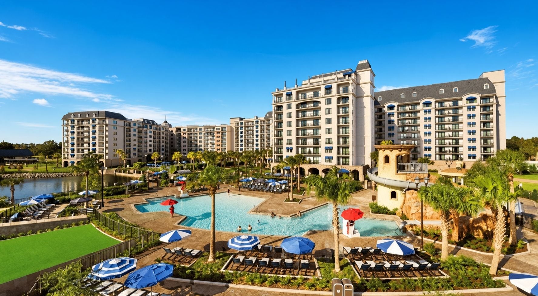 Un hôtel comprenant plusieurs bâtiments, un espace piscine agrémenté de parasols et un jardin aménagé.