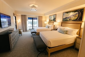 Ein Hotelzimmer mit zwei Betten, einem Schreibtisch, einem Fernseher und einem Gemälde.