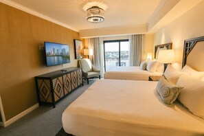 A hotel room with two beds, a TV, a desk, and a view of the city. - Orlando • Grand Family Escape • Pool + Resort • 3BR Sleeps 12 (Lake Buena Vista)