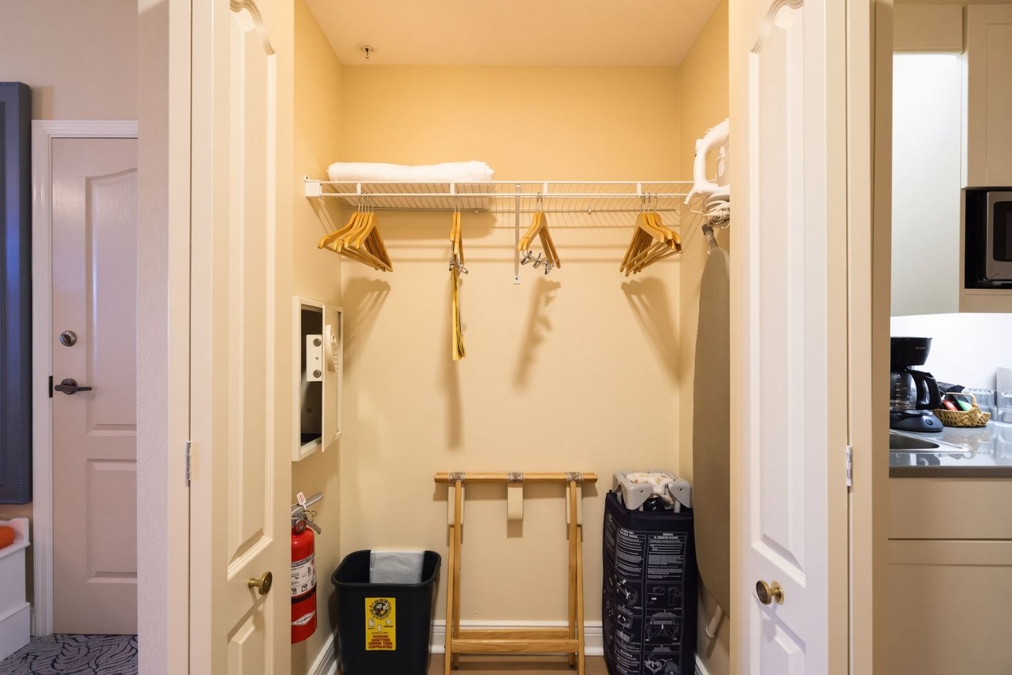 A narrow hallway with a coat rack, a fire extinguisher, and a trash bin.