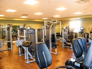 Un gimnasio con diversas máquinas de ejercicio y bancos.