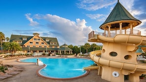 Un resort con una piscina grande, un tobogán acuático y un edificio con varios balcones.