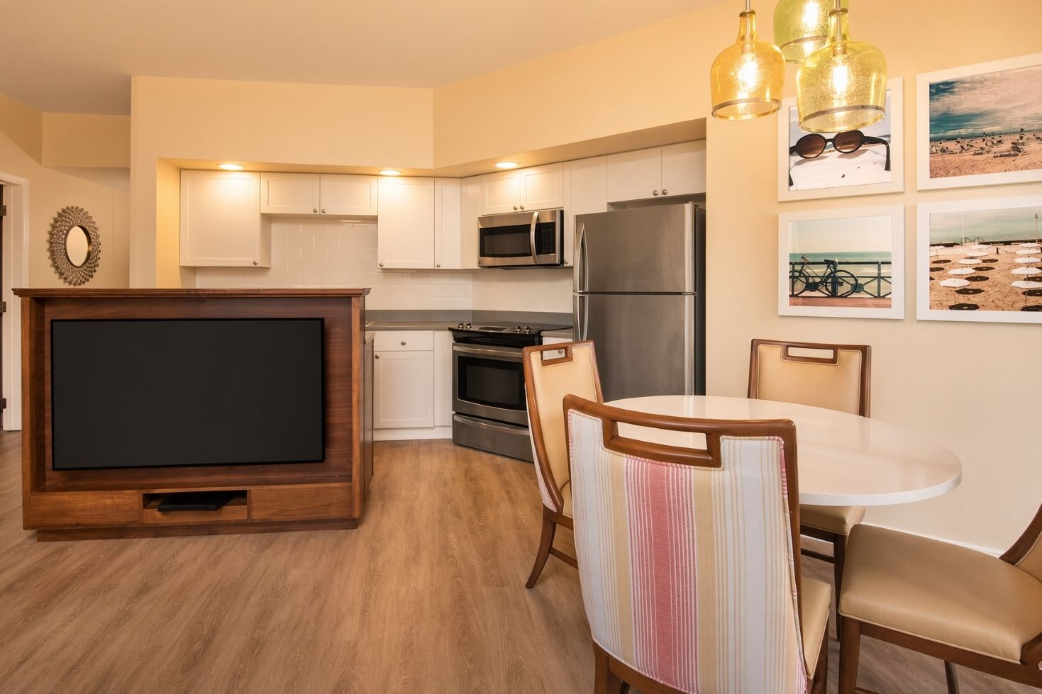 A modern kitchen with built-in appliances, a dining area with striped chairs, and wall-mounted artwork.