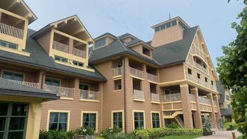 A multi-story hotel with balconies, a central courtyard, and a pathway leading to the entrance.
