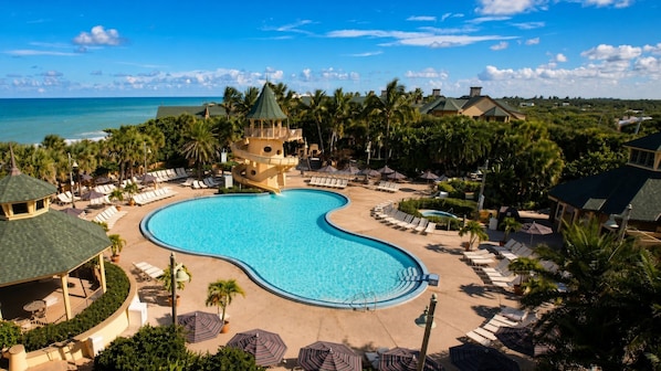 Un resort con una amplia piscina, sillas de descanso y una estructura tipo torre.